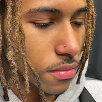 a man with dreadlocks and a nose piercing
