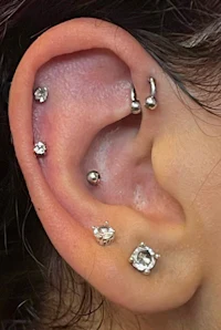 a woman's ear with several piercings